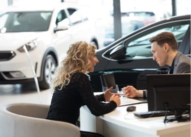 Man and woman looking at electronic car title at dealership